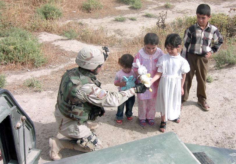 Photograph of an American soldier offering gifts to Iraqi children. Photograph by an American soldier of C Co, 1/252 Army Reserve Battalion. 